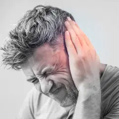 Hombre con mano en la oreja, sufriendo un intenso zumbido oido.