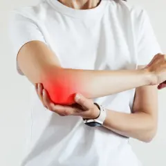 Persona con dolor en el codo, señalando la zona afectada. Busca alivio y un **artritis tratamiento** efectivo.