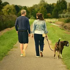Pareja pasea a su perro. El **reuma** no les impide disfrutar del **andar** por el campo.