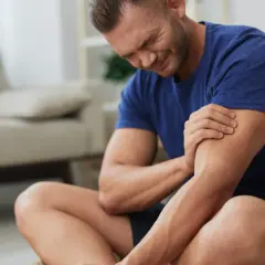 Hombre con expresión de dolor, sujetando su brazo. Sufre de dolores musculares tras un esfuerzo.