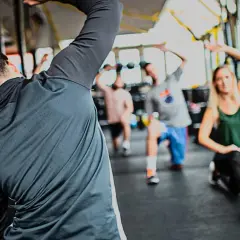 Personas realizando estiramientos dinámicos y estáticos en un gimnasio.