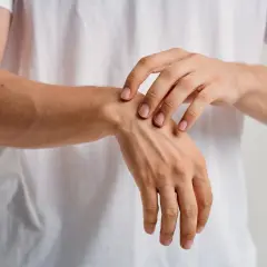 Un primer plano de un hombre tocando su muñeca, sintiendo los huesos de la mano bajo la piel.