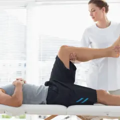 Fisioterapeuta realiza masajes deportivos a un atleta en camilla, enfocándose en la pierna y el pie para aliviar la tensión muscular.