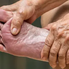 Manos arrugadas masajean un pie, aliviando el dolor de pies.