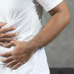Hombre con las manos en el abdomen, sintiendo una contractura abdominal.