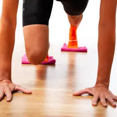 Manos en el suelo, rodillas flexionadas sobre discos deslizantes. Ejercicio para fortalecer rodilla.