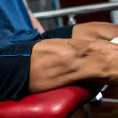 Primer plano de un hombre realizando ejercicios para cuadriceps en una máquina de gimnasio.