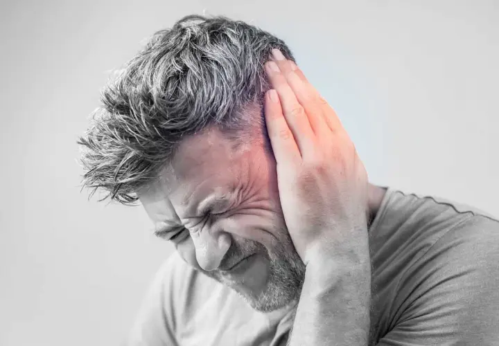 Hombre con mano en la oreja, sufriendo un intenso zumbido oido.