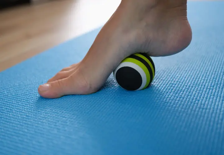 Pie con fascitis plantar rodando sobre una pelota de masaje. Descubre cómo eliminar la fascitis plantar en 72 horas con este sencillo ejercicio.