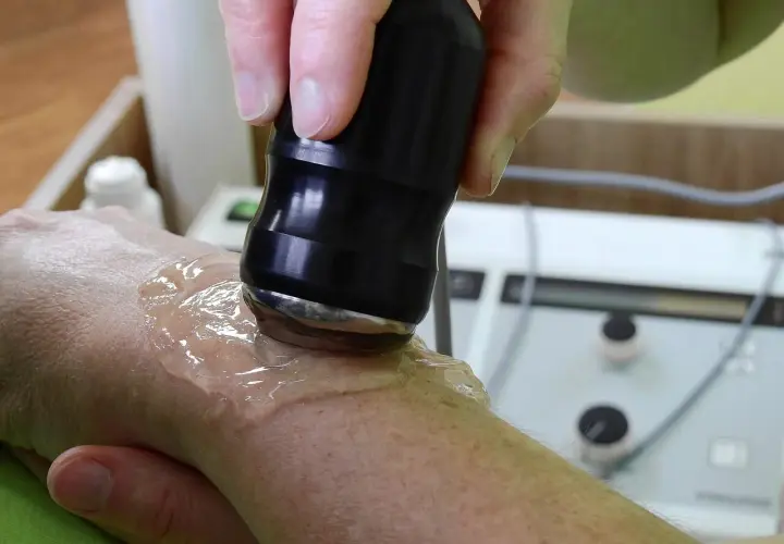 Tratamiento con ultrasonido para aliviar la tendinitis mano. Un profesional aplica gel y un dispositivo sobre la muñeca.