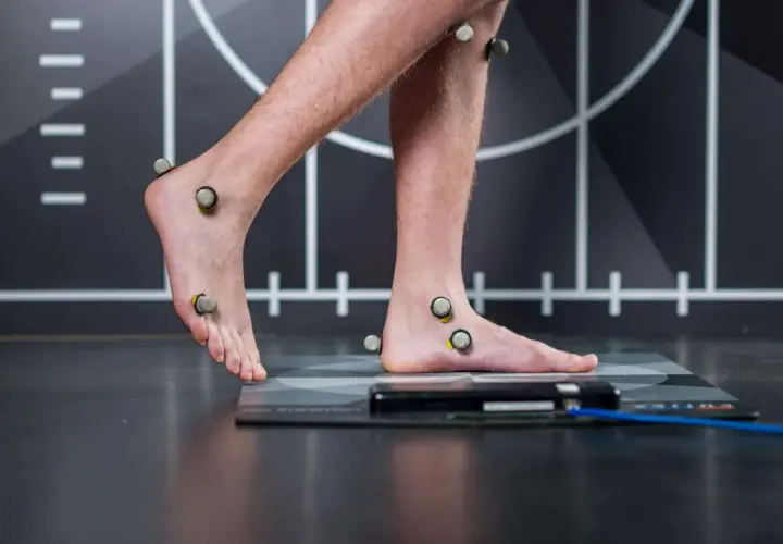 Persona con marcadores en pies y piernas para un estudio biomecánico de pisada.