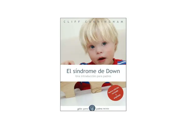 Un niño con síndrome de Down mira a la cámara. El libro "El síndrome de Down: Una introducción para padres" se muestra en la imagen.