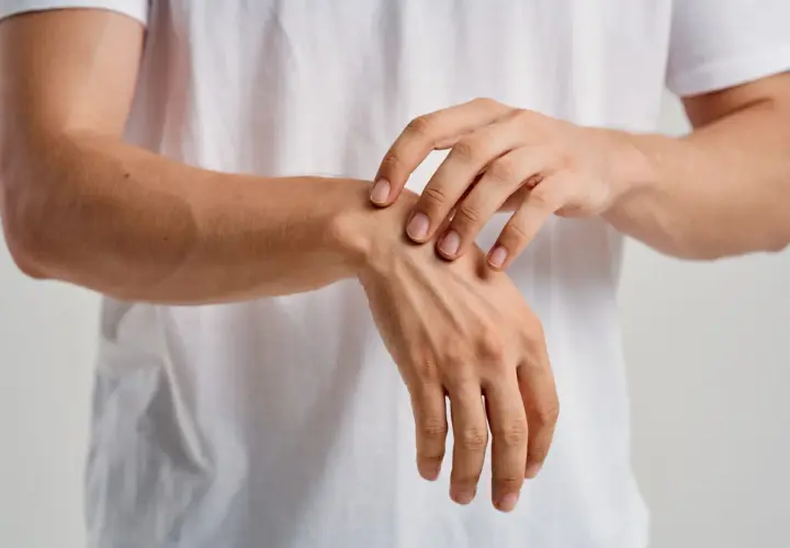 Un primer plano de un hombre tocando su muñeca, sintiendo los huesos de la mano bajo la piel.