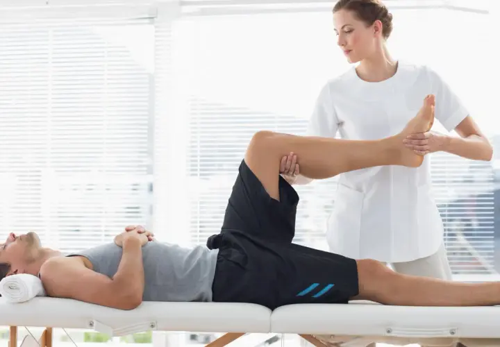 Fisioterapeuta realiza masajes deportivos a un atleta en camilla, enfocándose en la pierna y el pie para aliviar la tensión muscular.