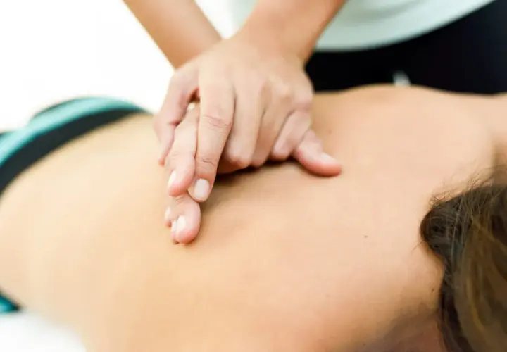 Manos expertas aplican masoterapia en fisioterapia para aliviar la tensión en la espalda de un paciente.