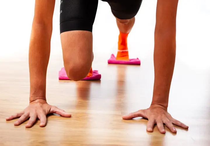 Manos en el suelo, rodillas flexionadas sobre discos deslizantes. Ejercicio para fortalecer rodilla.
