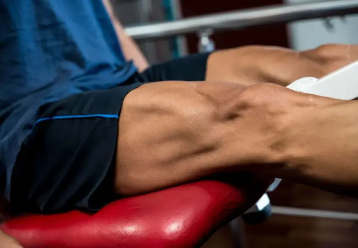 Primer plano de un hombre realizando ejercicios para cuadriceps en una máquina de gimnasio.