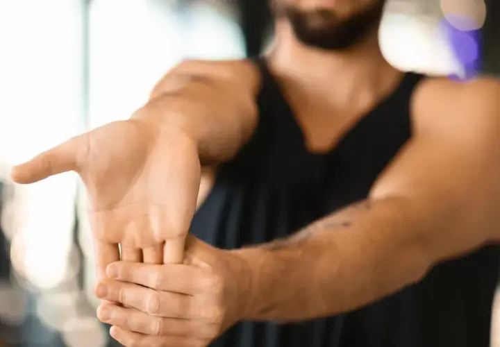 Hombre realizando ejercicios de estiramiento de muñeca para aliviar la tendinitis.