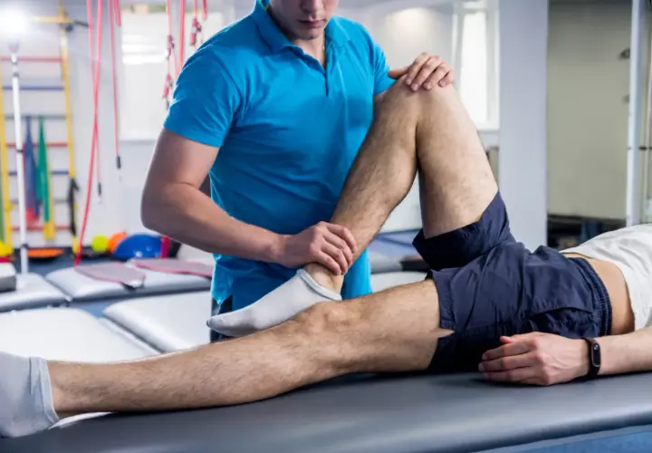 Fisioterapeuta examina la pierna de un paciente, ayudando a aliviar los síntomas de esclerosis múltiple.