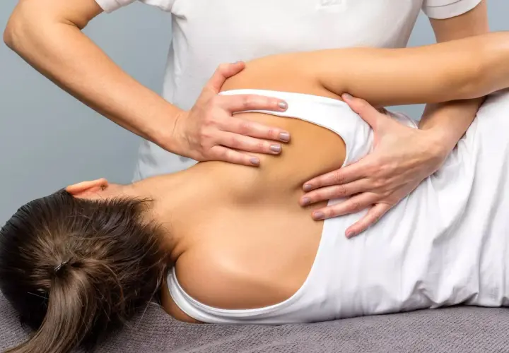 Fisioterapeuta realiza masaje en la espalda de una paciente, ayudando a aliviar el dolor asociado a la fibromialgia.