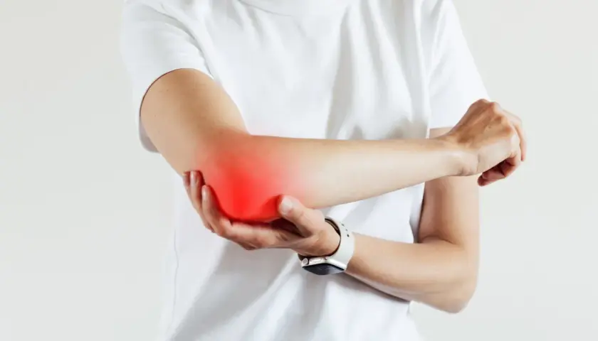 Persona con dolor en el codo, señalando la zona afectada. Busca alivio y un **artritis tratamiento** efectivo.