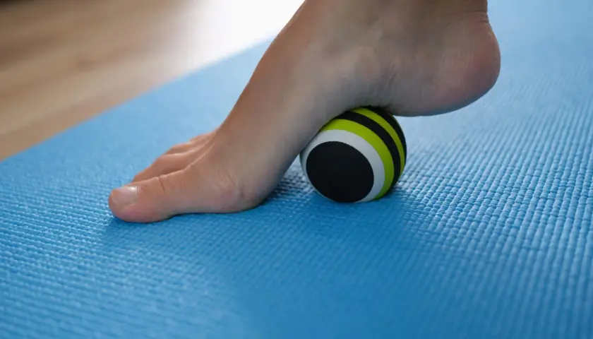 Pie con fascitis plantar rodando sobre una pelota de masaje. Descubre cómo eliminar la fascitis plantar en 72 horas con este sencillo ejercicio.