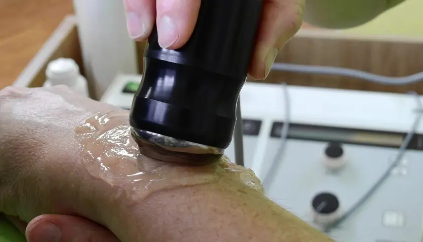 Tratamiento con ultrasonido para aliviar la tendinitis mano. Un profesional aplica gel y un dispositivo sobre la muñeca.