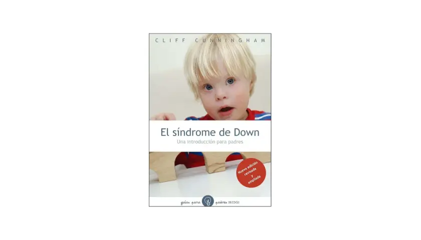 Un niño con síndrome de Down mira a la cámara. El libro "El síndrome de Down: Una introducción para padres" se muestra en la imagen.