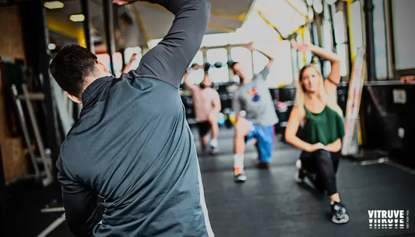 Personas realizando estiramientos dinámicos y estáticos en un gimnasio.