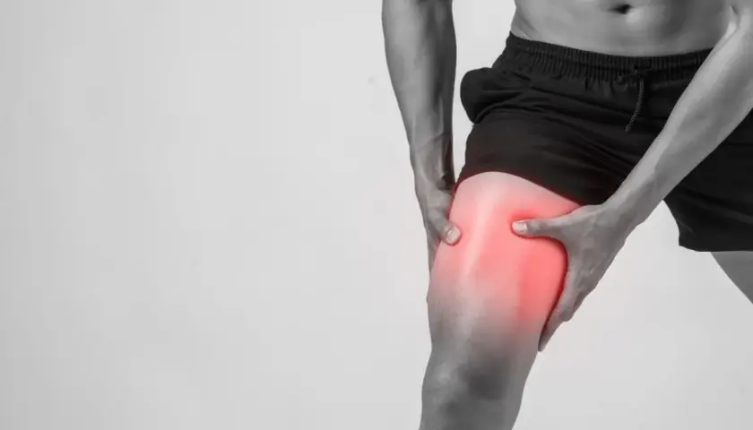 Hombre sujetando su muslo con un área enrojecida, indicando dolor muscular después de entrenar.