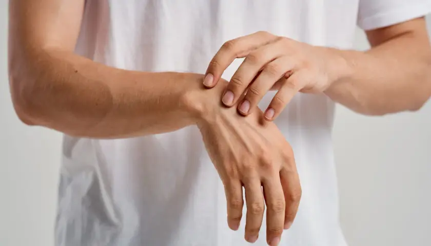 Un primer plano de un hombre tocando su muñeca, sintiendo los huesos de la mano bajo la piel.