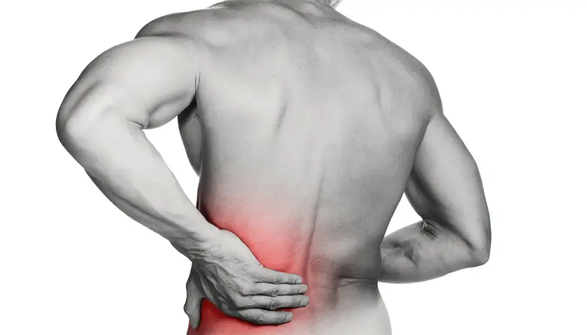 Hombre con mano en la zona lumbar, marcada en rojo, indicando dolor. ¿Cómo saber si tengo lumbago?