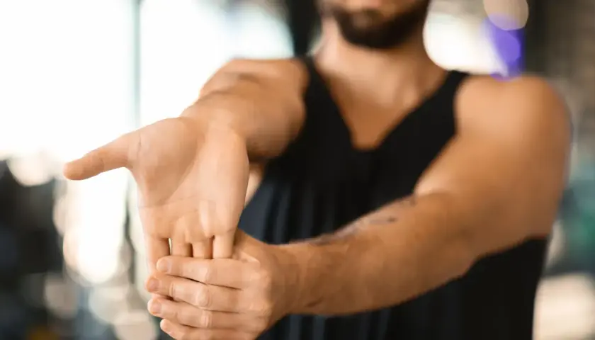 Hombre realizando ejercicios de estiramiento de muñeca para aliviar la tendinitis.