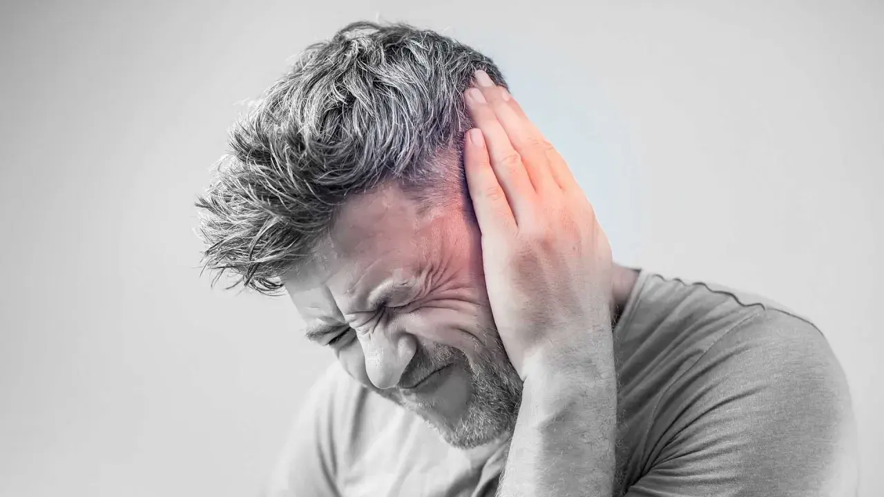 Hombre con mano en la oreja, sufriendo un intenso zumbido oido.