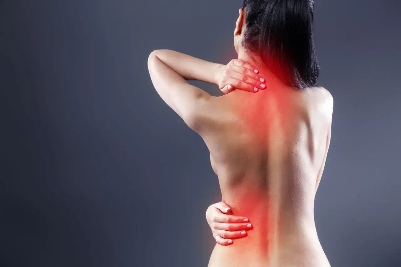 Mujer con dolor de espalda, mostrando los síntomas de dorsalgia en cuello y zona lumbar, con zonas rojas de inflamación.