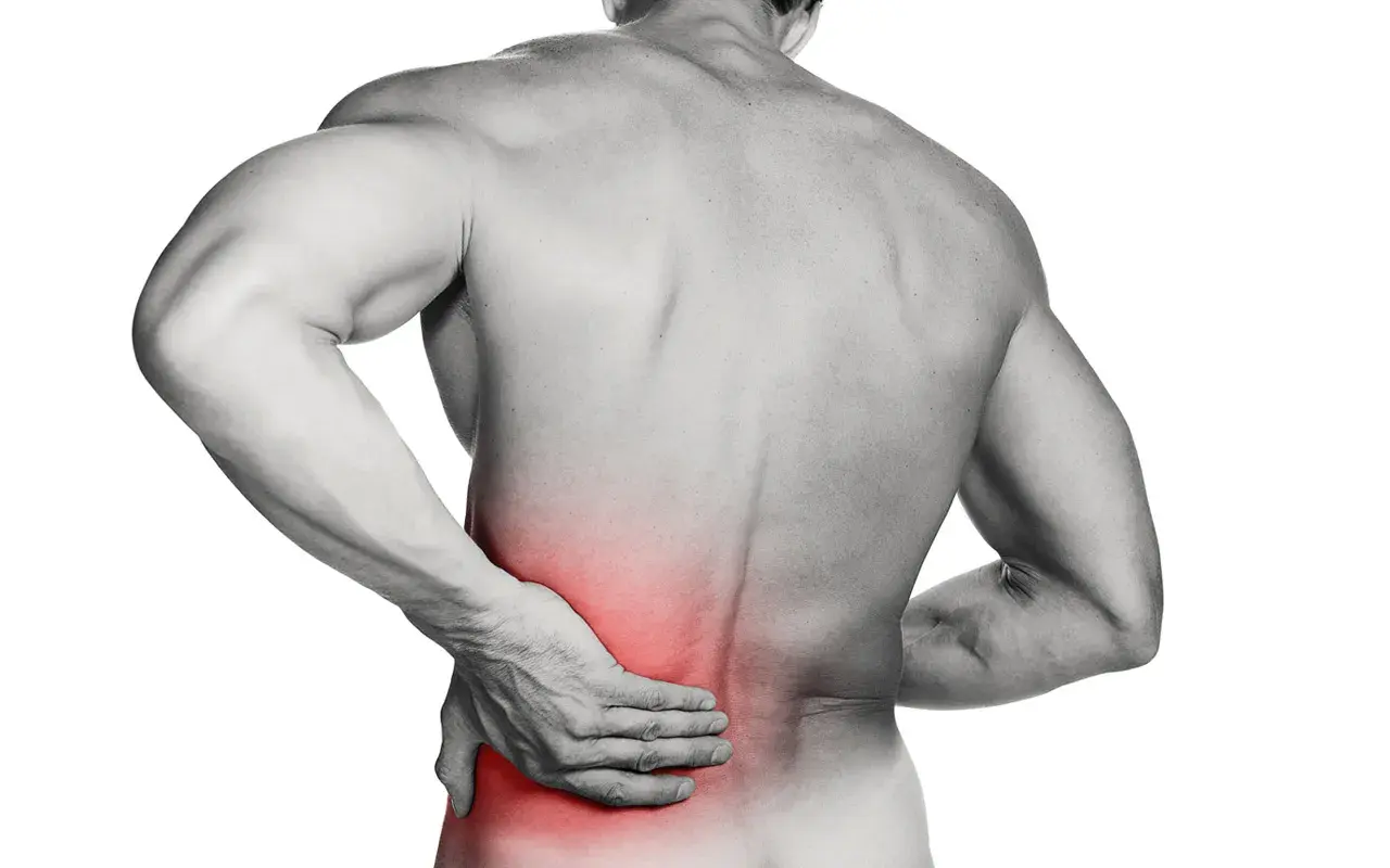 Hombre con mano en la zona lumbar, marcada en rojo, indicando dolor. ¿Cómo saber si tengo lumbago?