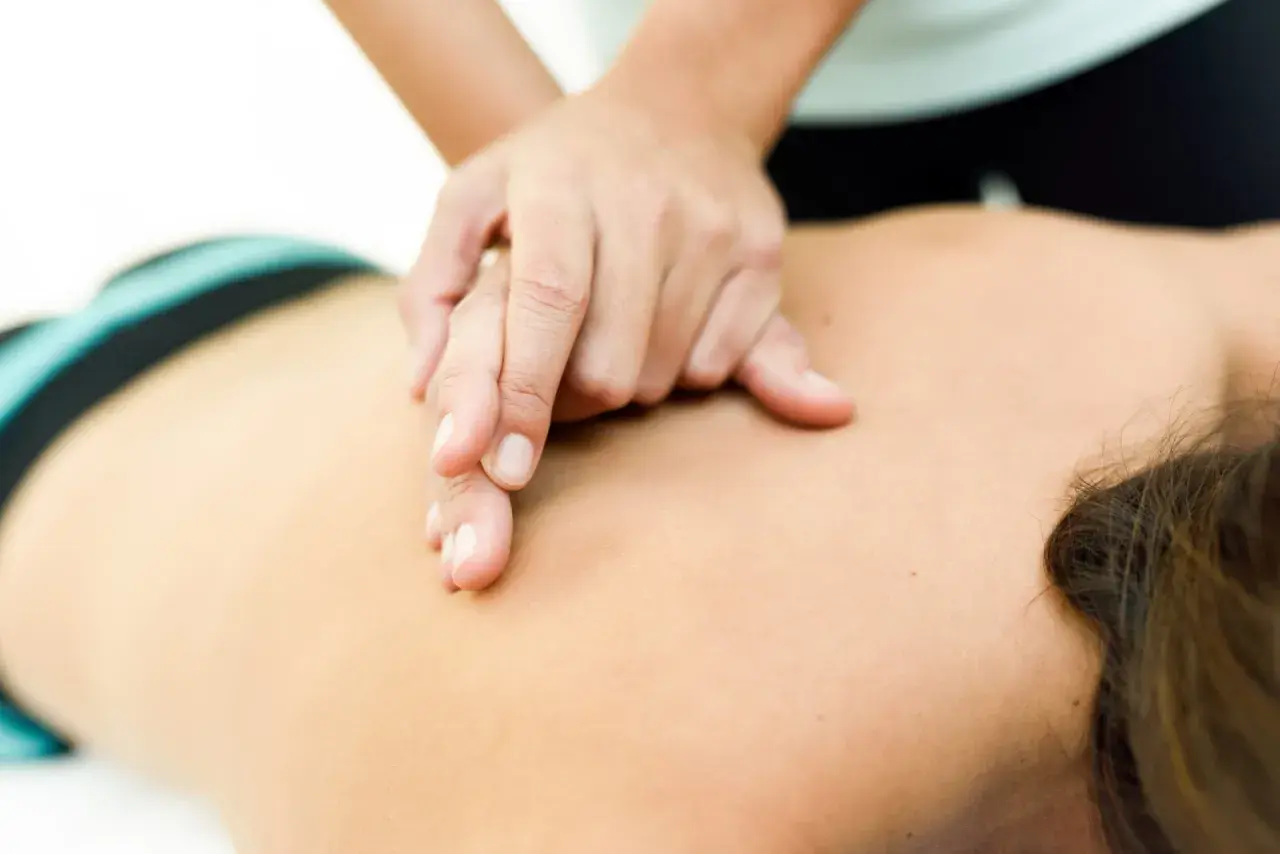 Manos expertas aplican masoterapia en fisioterapia para aliviar la tensión en la espalda de un paciente.
