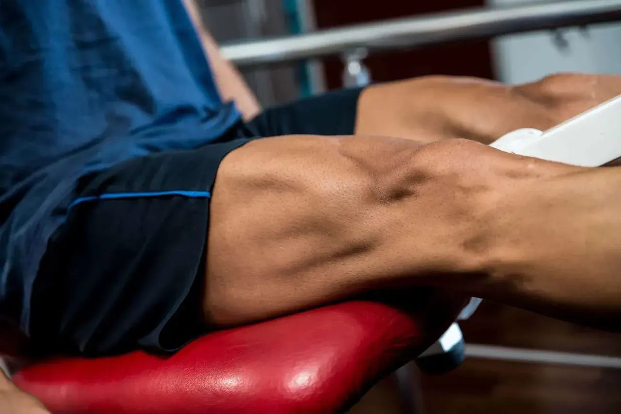 Primer plano de un hombre realizando ejercicios para cuadriceps en una máquina de gimnasio.