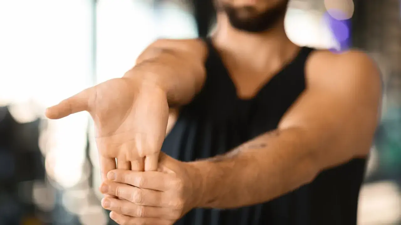 Hombre realizando ejercicios de estiramiento de muñeca para aliviar la tendinitis.