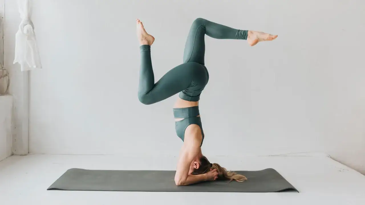 Mujer en postura de pino sobre una esterilla. El yoga es un deporte que requiere fuerza y equilibrio.