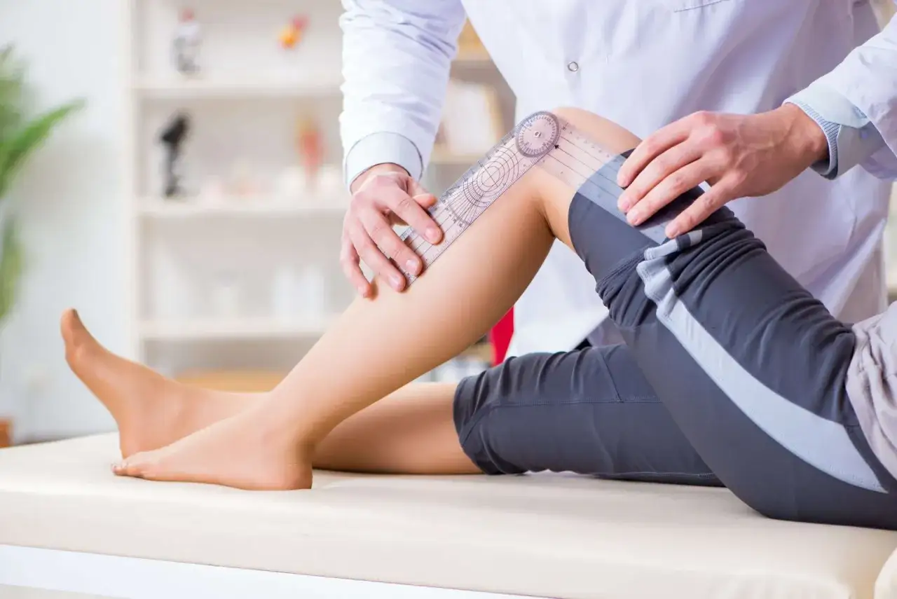 Fisioterapeuta mide el rango de movimiento articular de la rodilla de un paciente con un goni&oacute;metro.