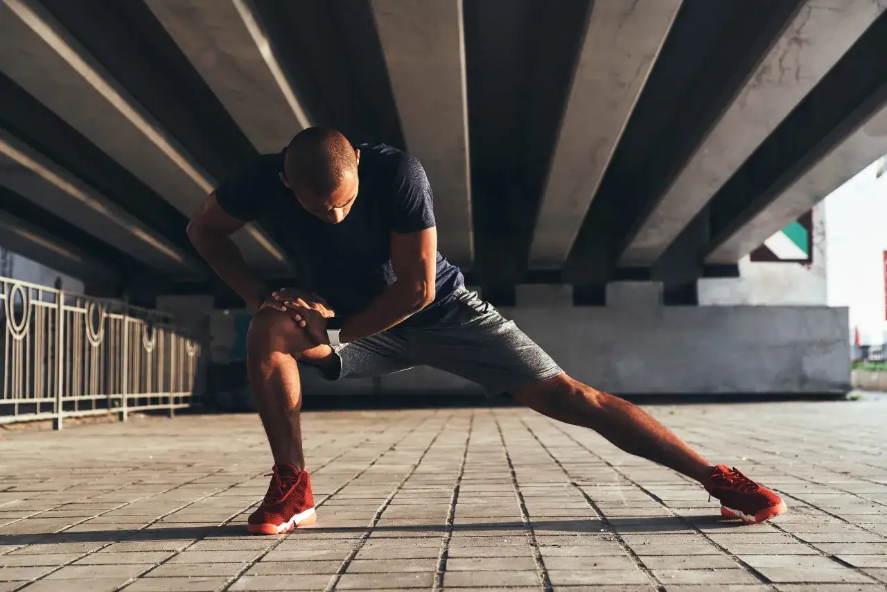 Hombre estirando bajo un puente, sintiendo que le fallan las piernas despu&eacute;s del ejercicio.