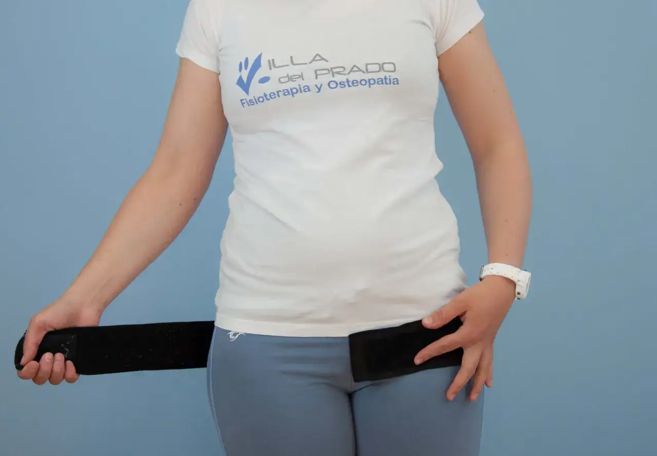 Mujer ajustando una faja postparto negra. La faja ayuda a la recuperación y soporte abdominal.