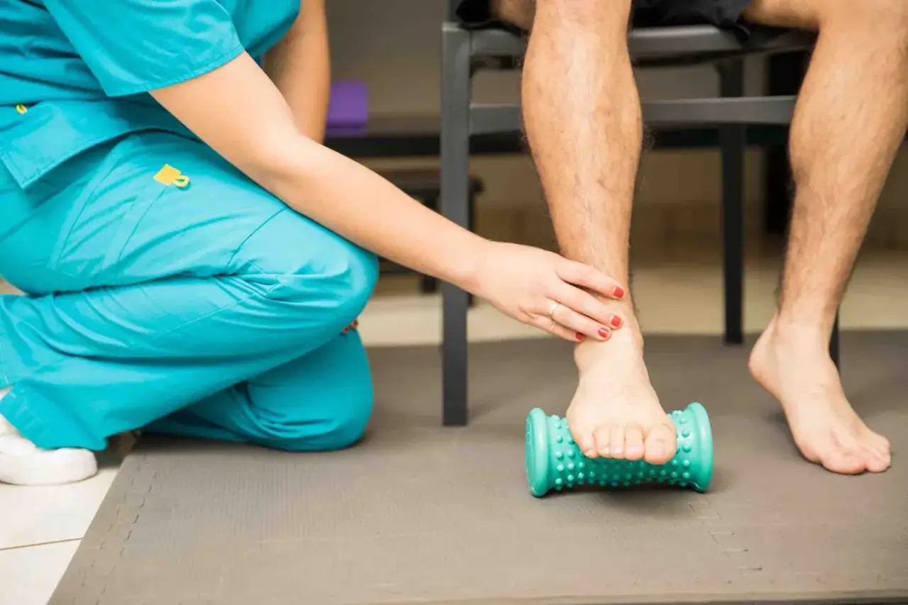 Fisioterapeuta ayuda a paciente a aliviar dolor con rodillo para fascitis plantar. Descubre cómo eliminar la fascitis plantar en 72 horas.