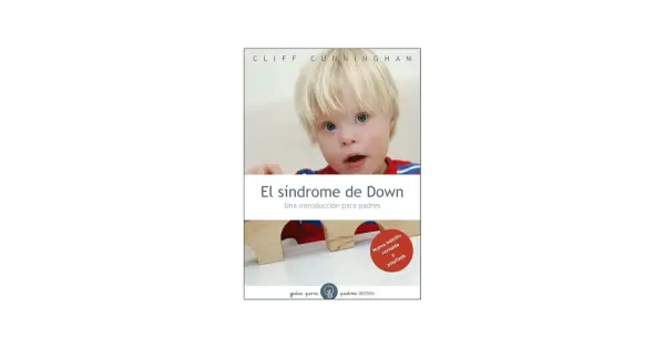 Un niño con síndrome de Down mira a la cámara. El libro "El síndrome de Down: Una introducción para padres" se muestra en la imagen.