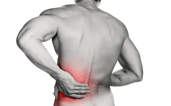 Hombre con mano en la zona lumbar, marcada en rojo, indicando dolor. ¿Cómo saber si tengo lumbago?