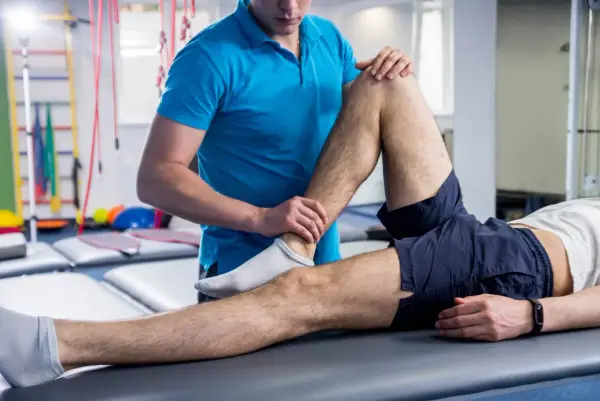 Fisioterapeuta examina la pierna de un paciente, ayudando a aliviar los síntomas de esclerosis múltiple.